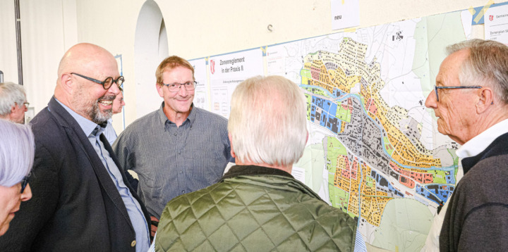 Gemeindepräsident Peter Buser (mitte) stellt sich den kritischen Fragen aus der Bevölkerung zum Entwurf des Zonenplans Siedlung. Viktor Holzemer vom Ingenieurbüro Jermann (links) zeigt sich gut gelaunt. Bild Nikolaos Schär