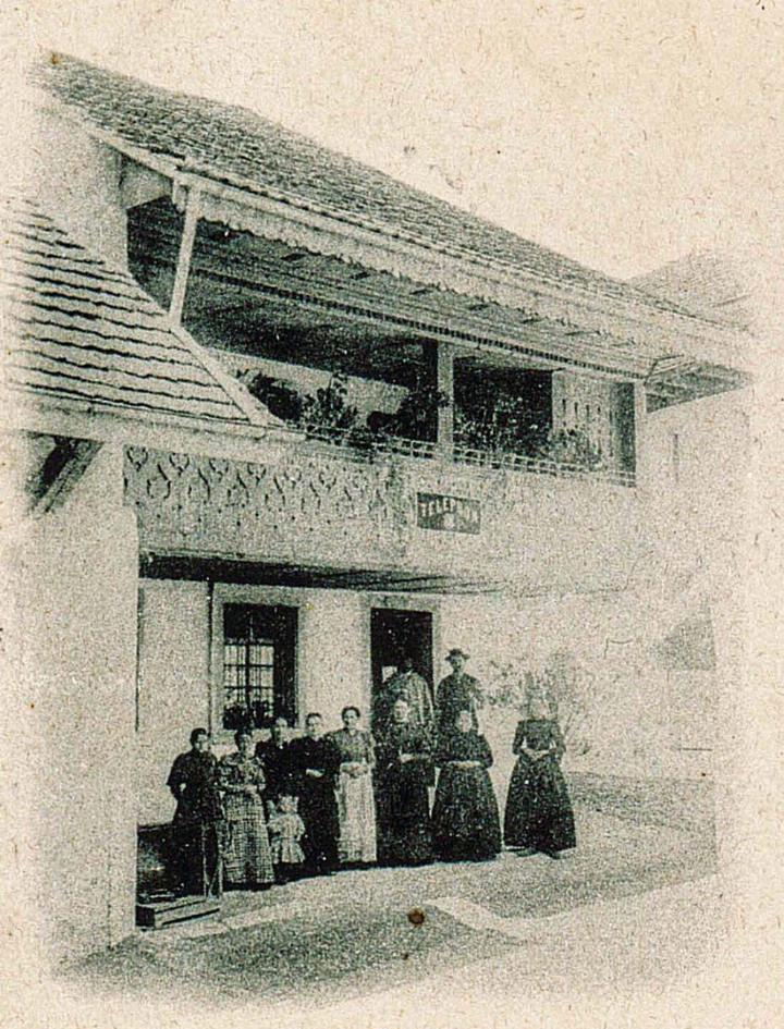 Diese Fotografie stammt aus der Zeit um 1900 und zeigt das ehemalige Bauernhaus mit Restaurant im Hochparterre mit höherem Wohnteil und niedrigerer Scheune. Das Schild an der Laube belegt die Präsenz eines Telefons im Haus.