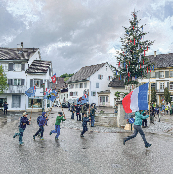 Die Fahnenträgerin rennt zum Abschluss um den Dorfbrunnen – dicht gefolgt von den Wimpeln der vier Rotten. Bild Cyrill Laube