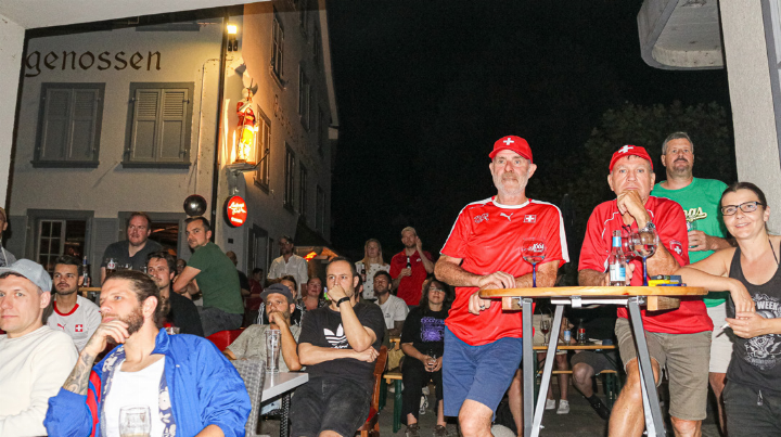 Die Fussballfans fokussieren gebannt die Leinwand in der Garage.